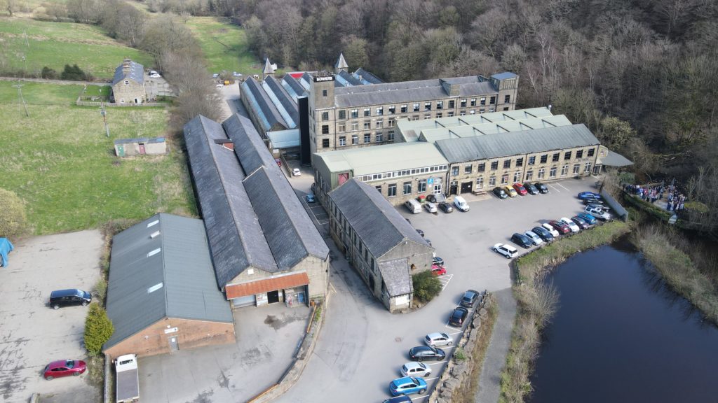 The full complex from the air: weaving sheds, tower and mill pond, spring 2023